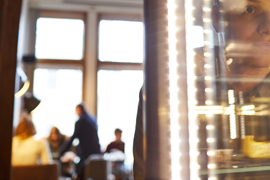 Grupo al fondo y persona delante mirando por la ventana