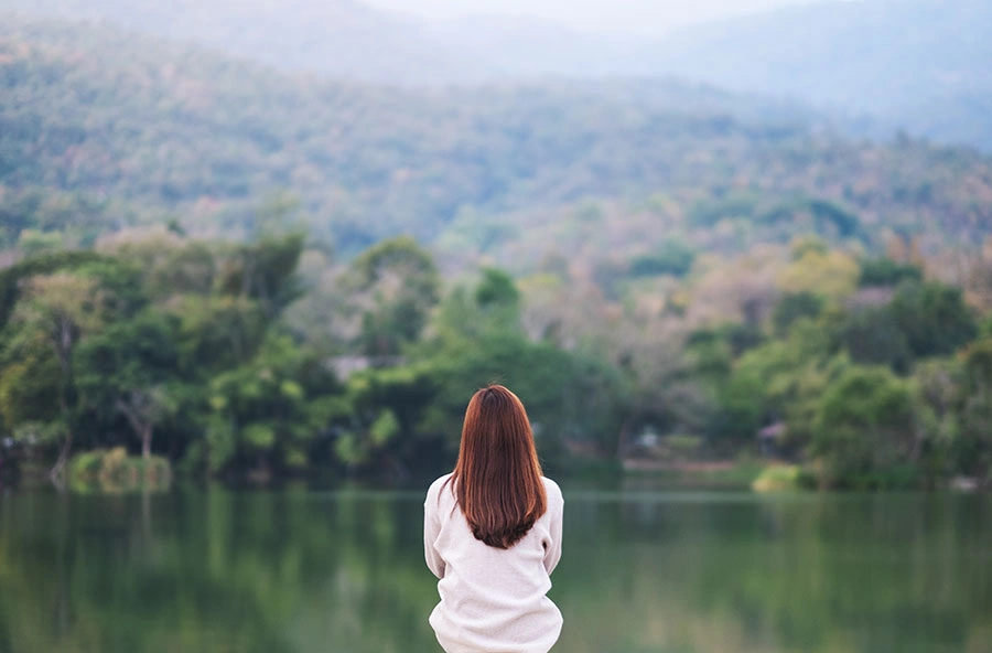 Mujer sentada delante de lago